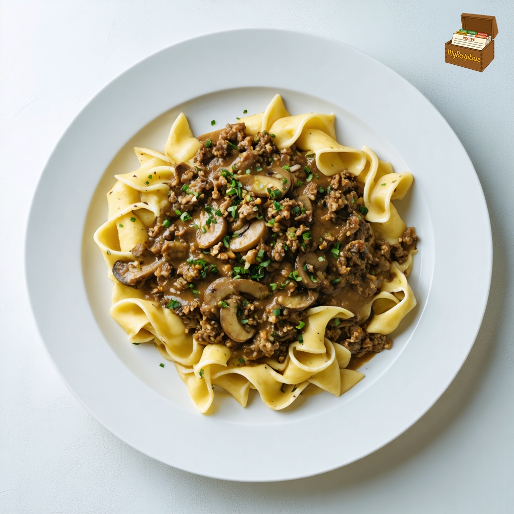An image of Ground Beef Stroganoff, captured from a three-quarter angle, slightly above the dish, elegantly plated for fine dining on a large plate. The stroganoff features a creamy sauce with visible bits of ground beef, mushrooms, and onions, served over egg noodles. The entire contents are displayed on a white table in a bright modern bistro, highlighting the contrast between the rich colors of the dish and the minimalist setting.